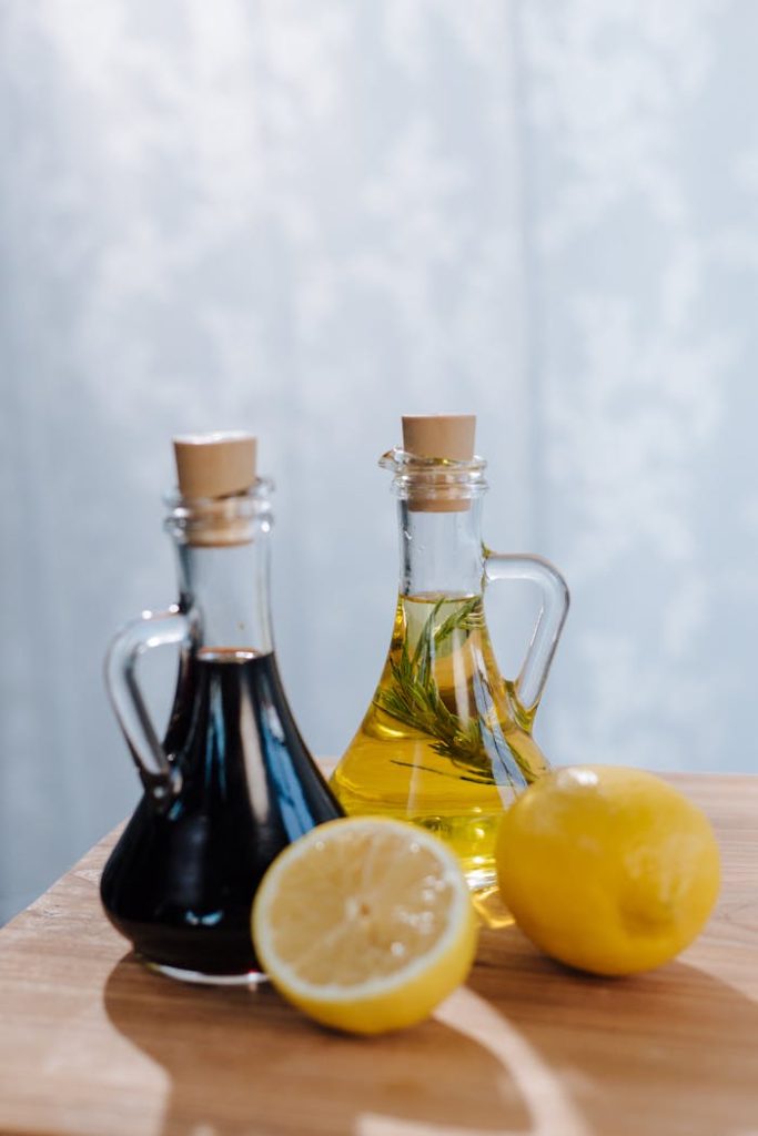 Halved lemon with Italian olive oil and balsamic vinegar set on a wooden surface.