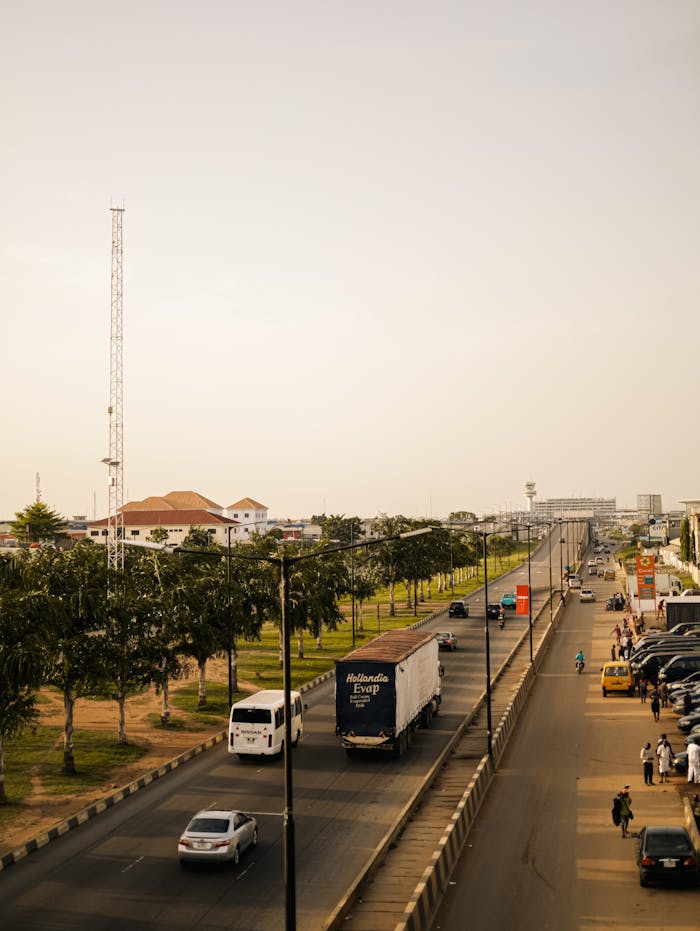 Aerial view of a city road with vehicles and trees lining the street.