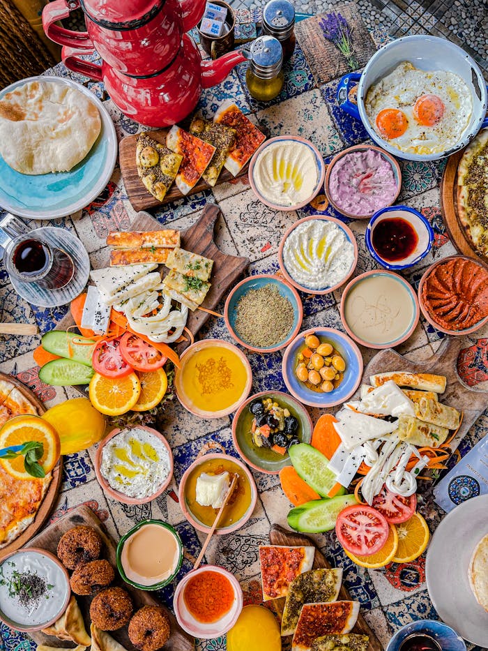 A vibrant flat lay of assorted Mediterranean breakfast dishes on decorated tiles.